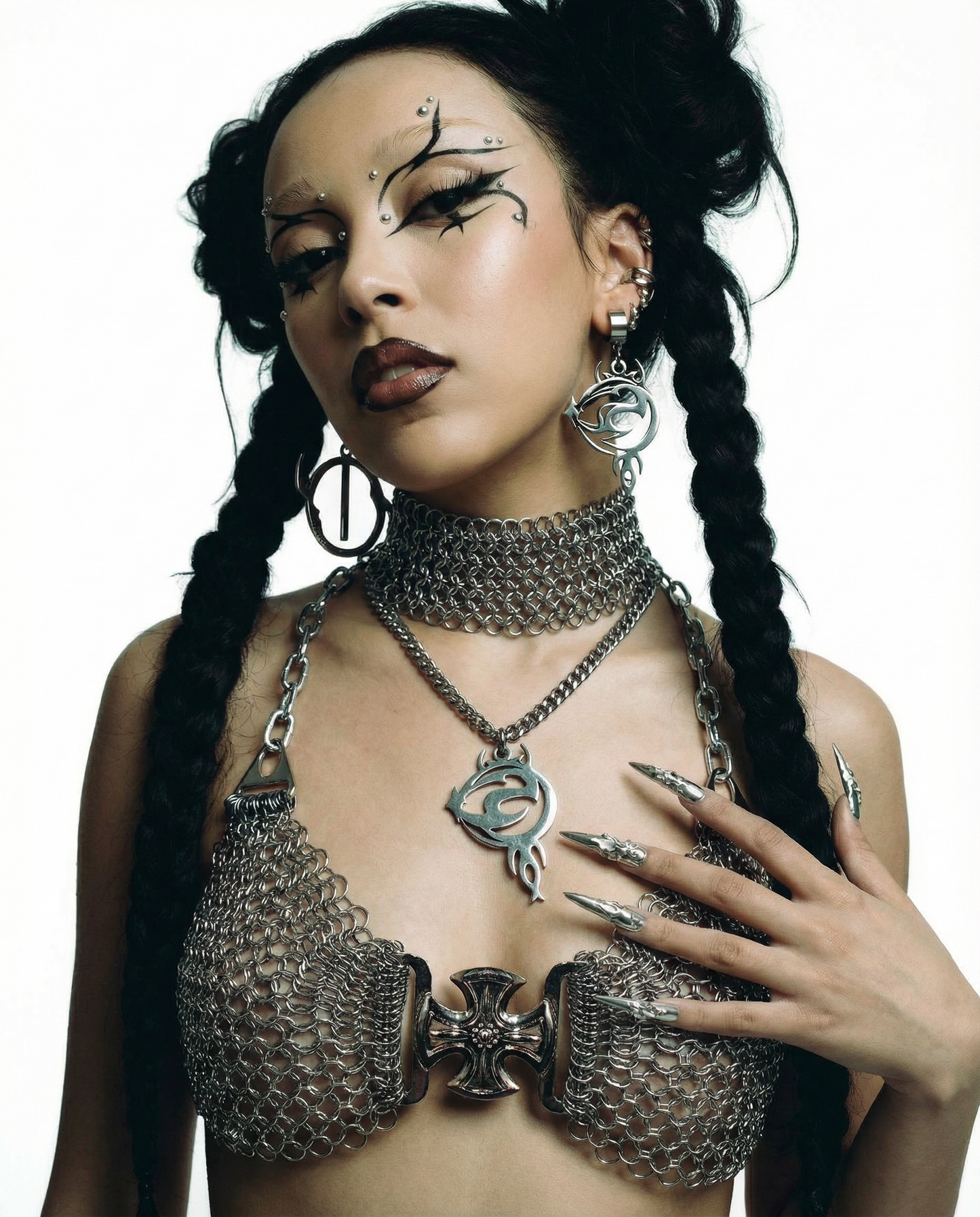 Woman wearing a chainmail outfit with intricate jewelry and makeup on a white background